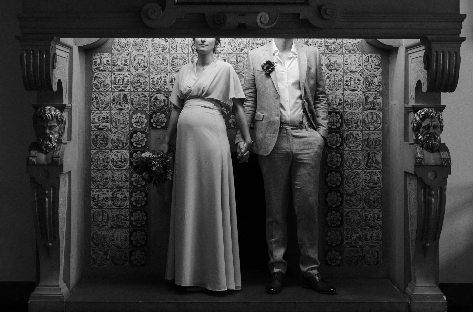 A bride and groom posing in front of a patterned wall