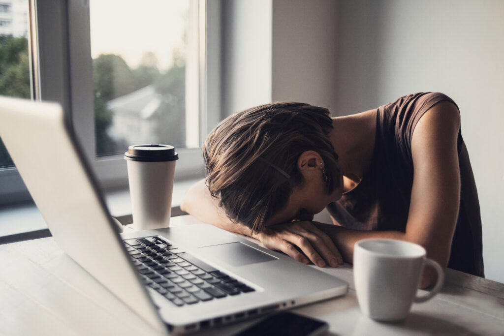 Tired photographer is sleeping on a table with laptop computer after processing a lot of photographs